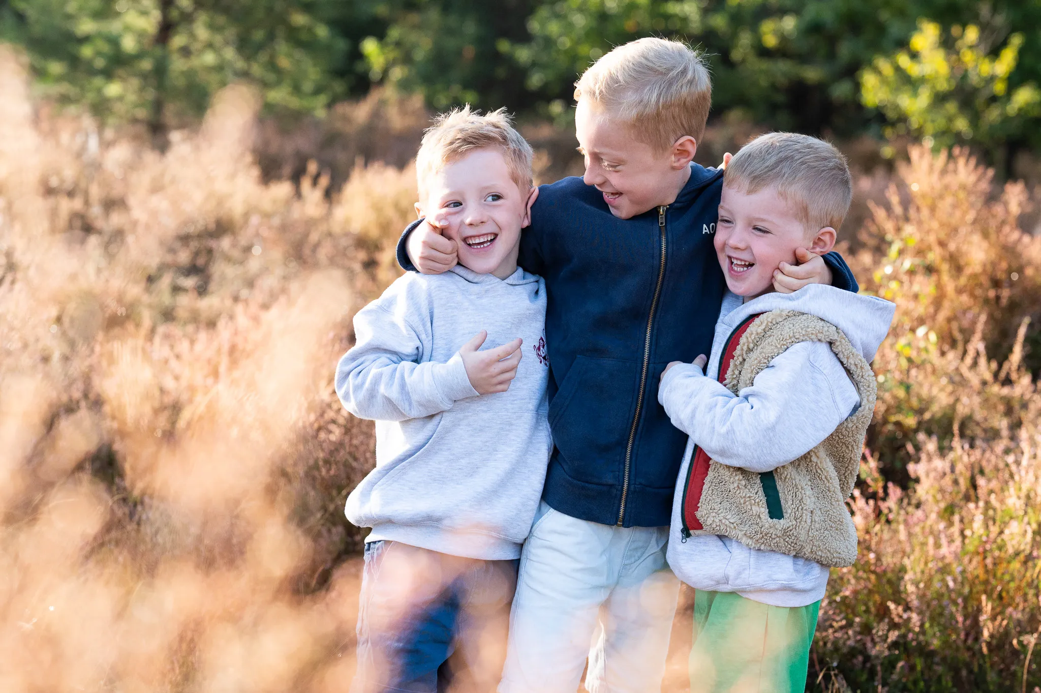 Spontane kinderfoto van drie jongens die samen lachen in de natuur – gezinsfotografie en kindershoot door fotograaf