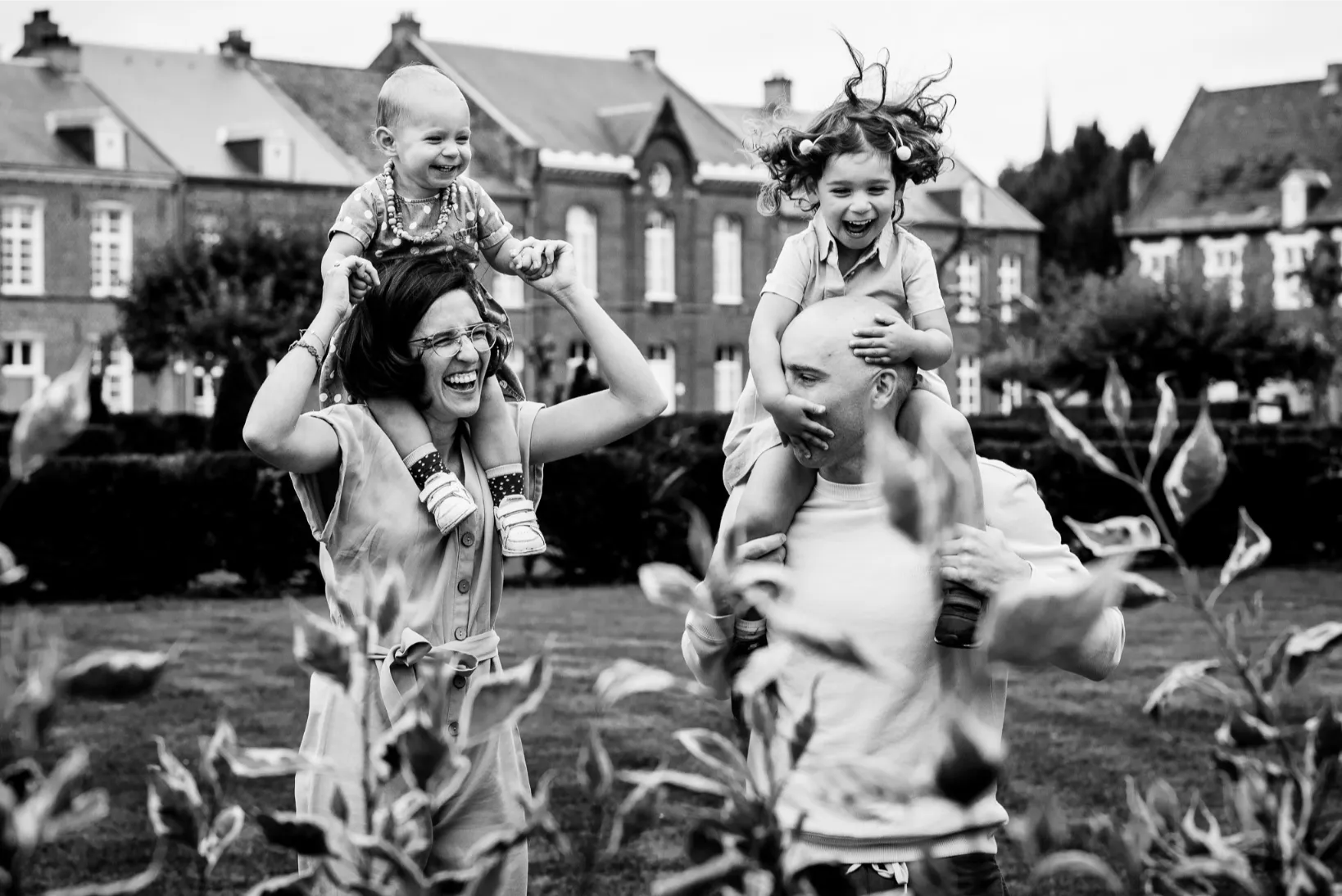Luchtige en speelse gezinsfoto op locatie met kinderen op de schouders, vastgelegd door een lifestyle fotograaf