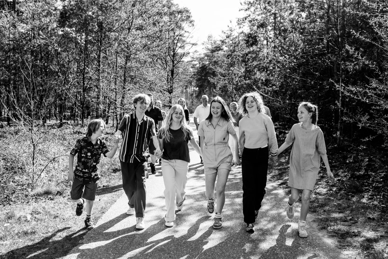 Ongeposeerde familieshoot in de natuur met tieners en kinderen die samen plezier maken