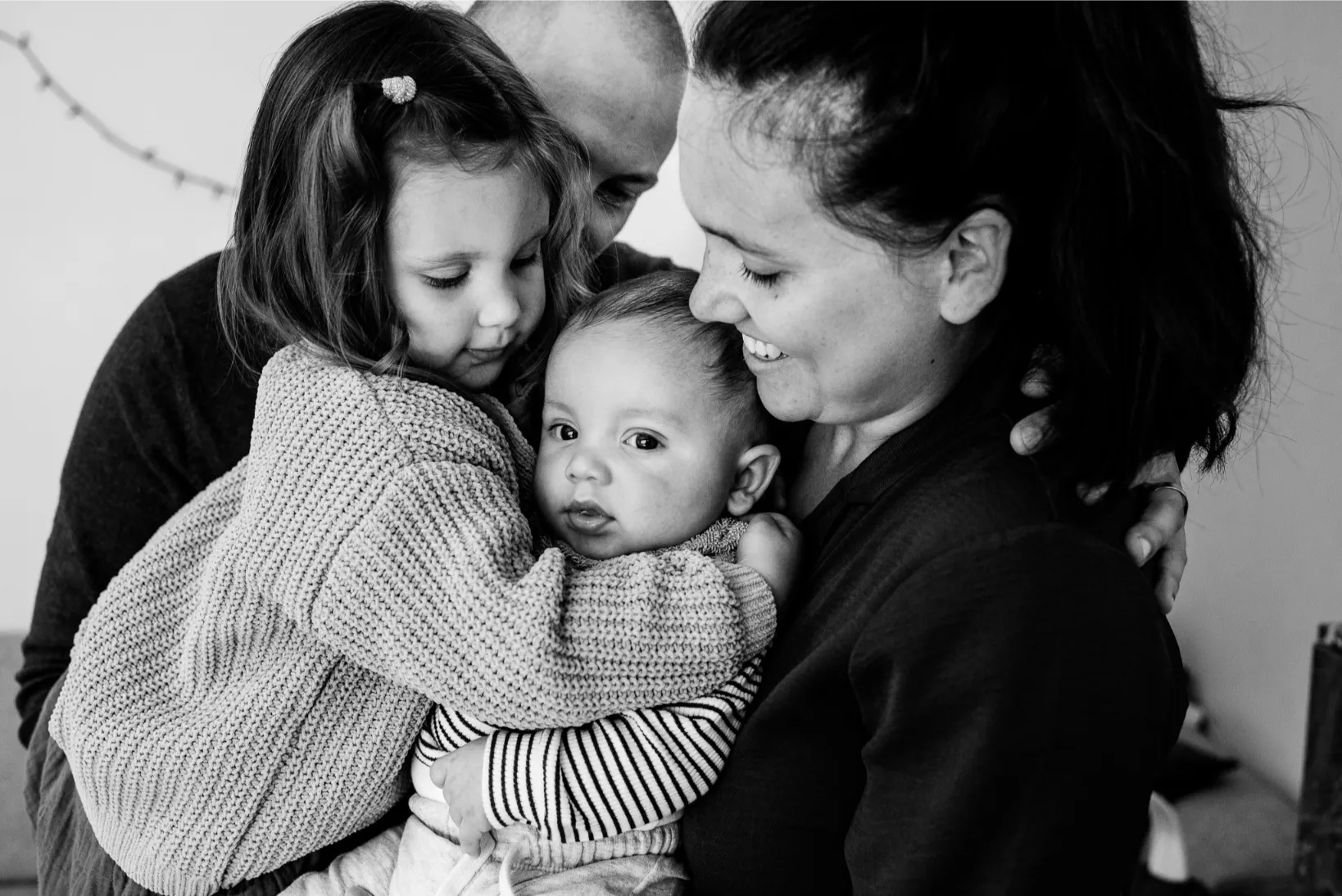 Warme en tedere gezinsfoto binnenshuis, met focus op verbinding tussen ouders en kinderen