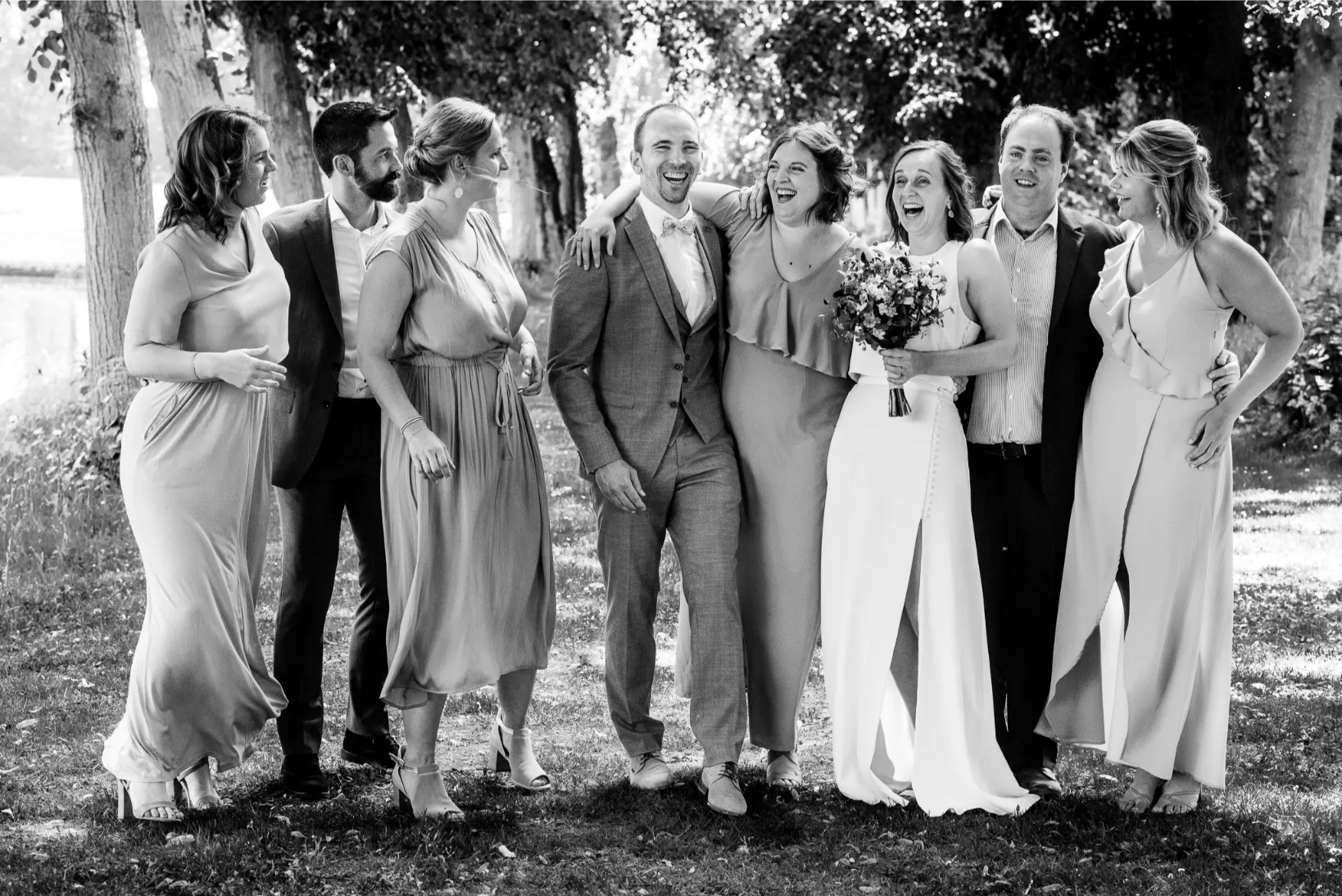 Groepsfoto vol energie en plezier van een bruidspaar met hun beste vrienden.