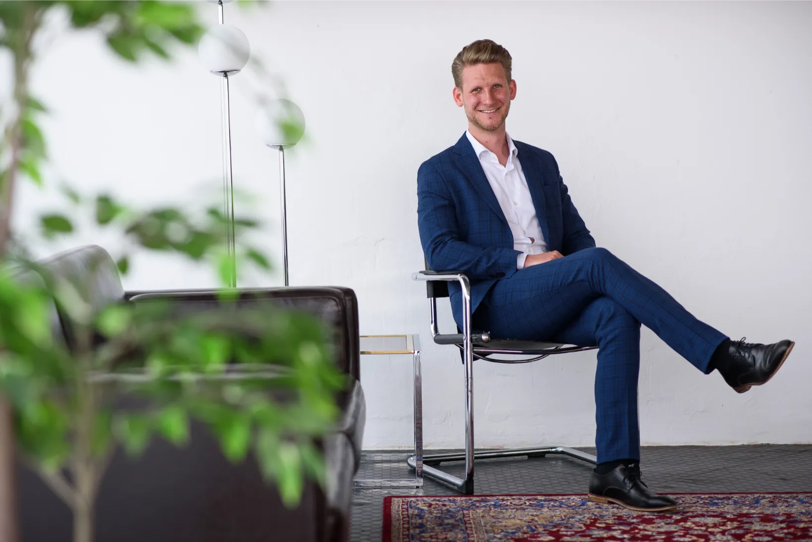 Zittend portret van een man in kostuum in een minimalistisch interieur, zakelijke profielfoto met rustige uitstraling.