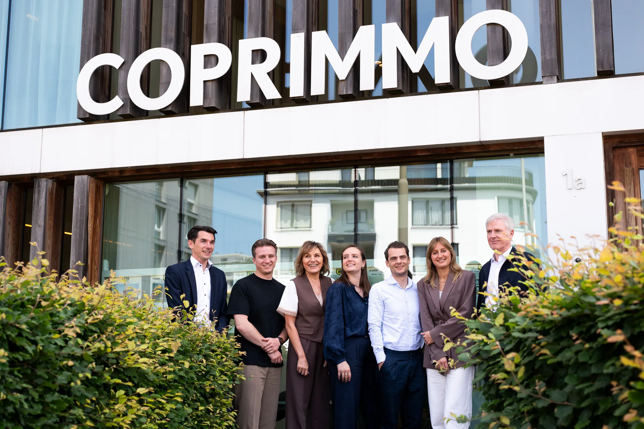 Teamfoto voor gebouw met Coprimmo logo – branding shoot vastgoedkantoor in Berchem